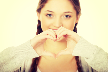 49479033 - smiling teen woman making heart shape with her hands.